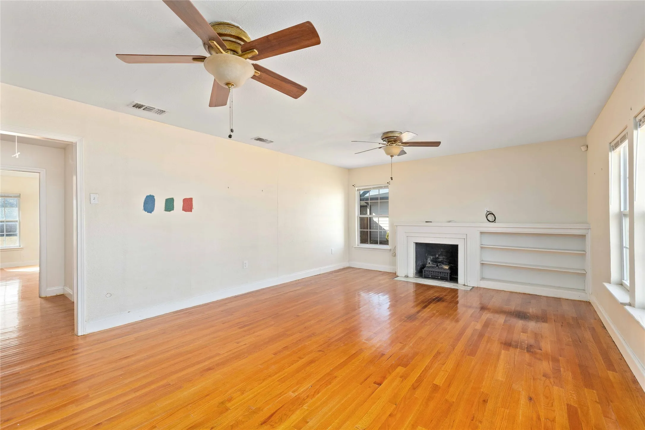 living room with a fireplace with flush hearth, light wood-type flooring, a ceiling fan, and attic access