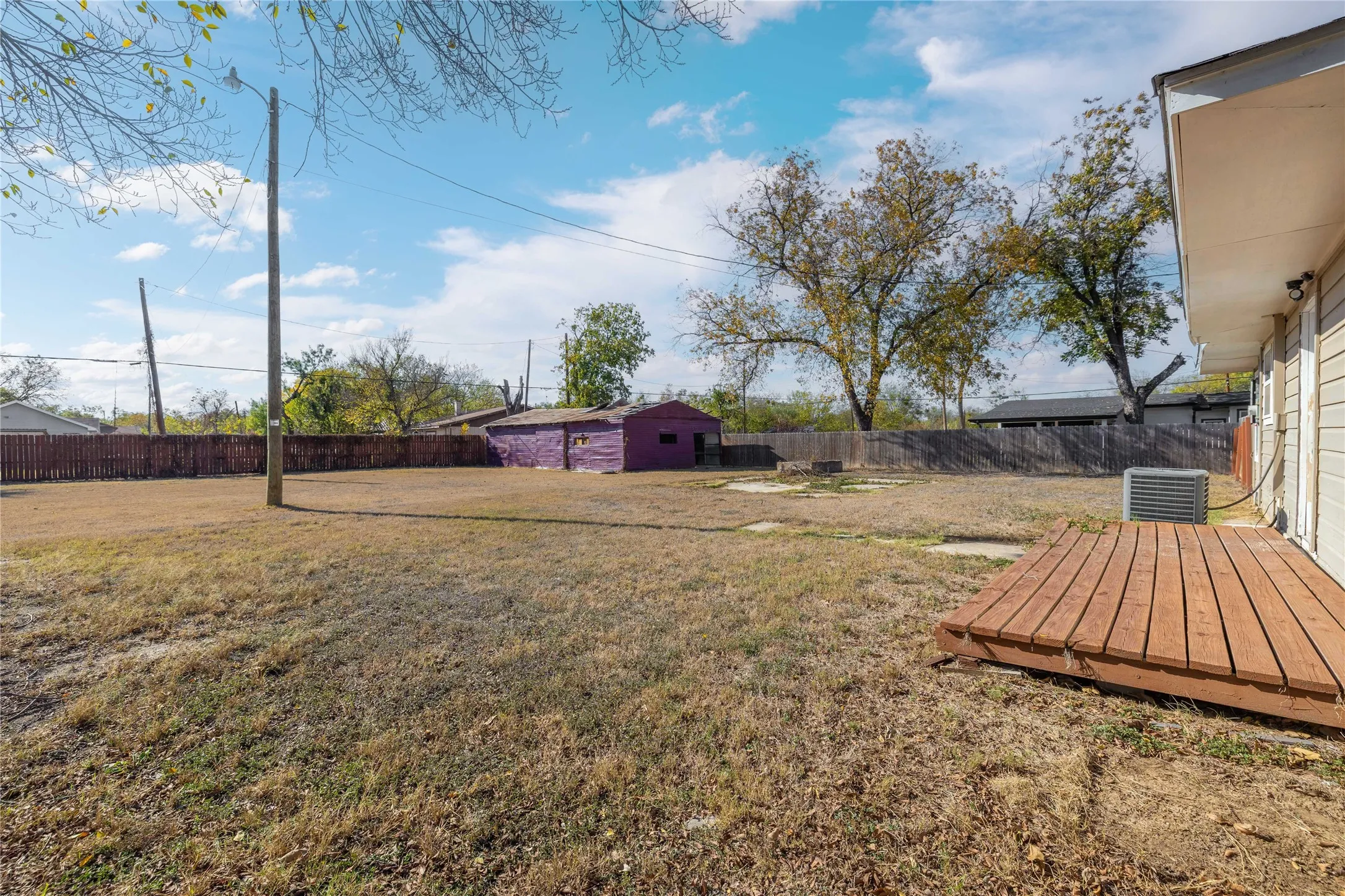 Fenced backyard featuring an outbuilding and a wooden deck