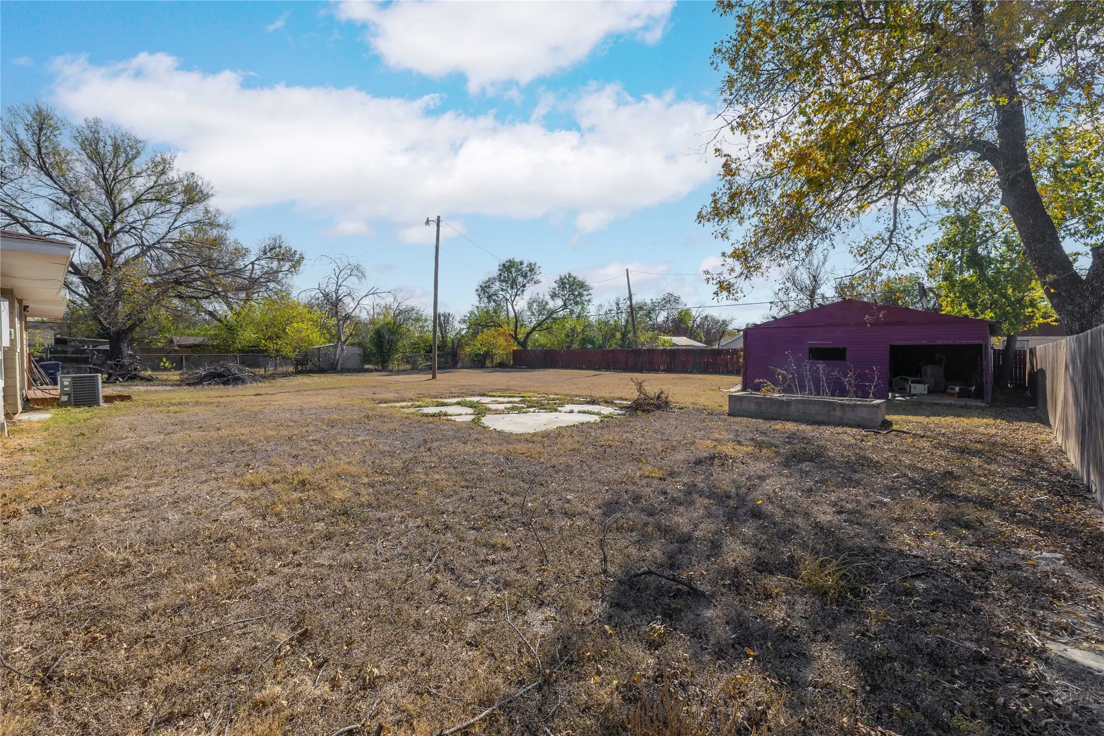 Fenced backyard featuring a patio area and an outbuilding