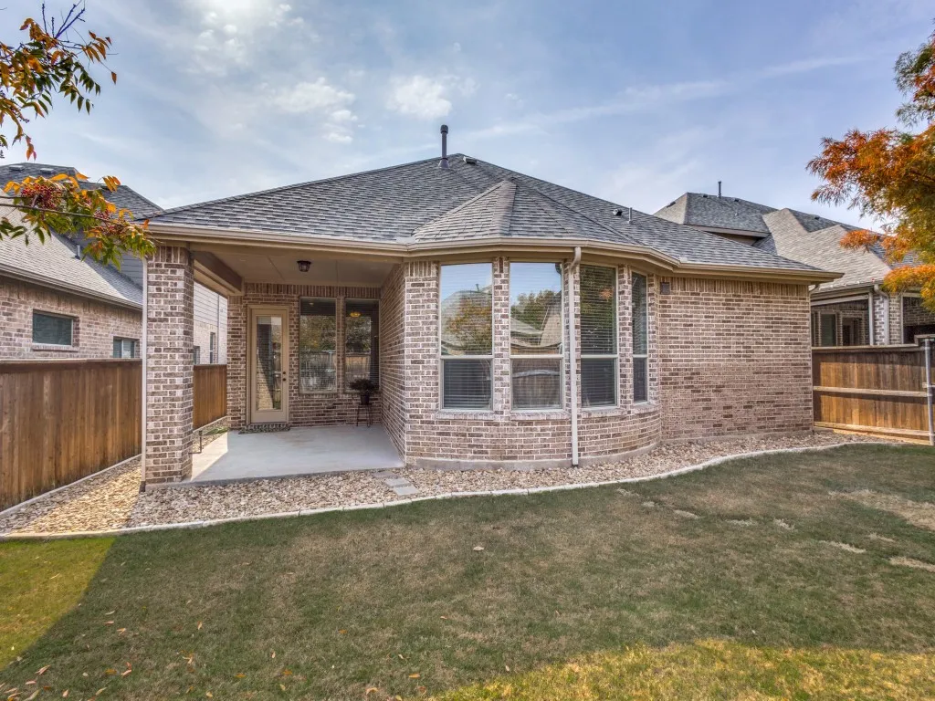 Rear view of house featuring a fenced backyard, a patio area, and brick siding.