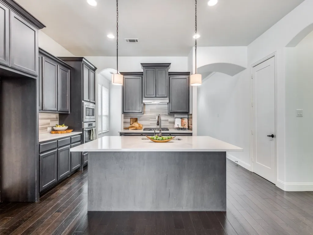 Kitchen with arched walkways, tasteful backsplash, dark wood finished floors, decorative light fixtures, and recessed lighting.