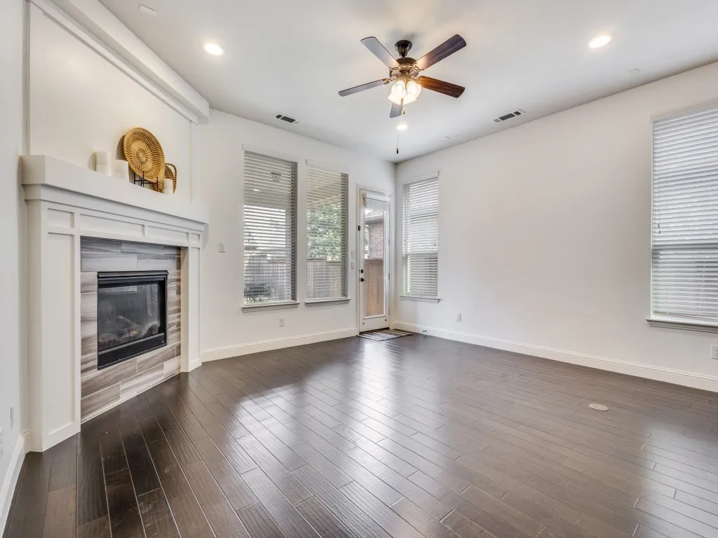 An angled, fireplace with mantle, recessed lighting, and ceiling fan finish out the den.