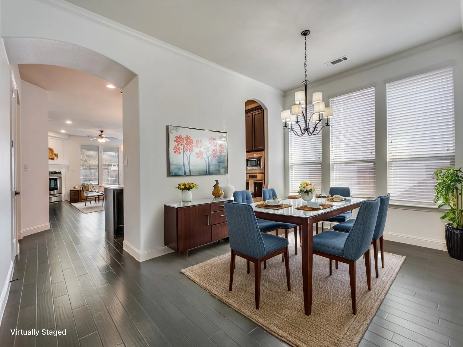 Formal dining area featuring dark wood-finish flooring, a contemporary chandelier, and three large windows with blinds