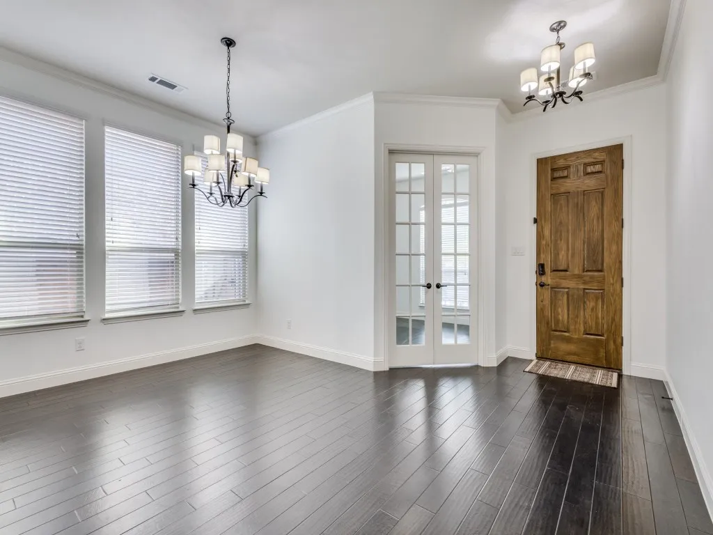Entryway featuring chandeliers, ornamental molding, French doors, and dark wood finished floors.