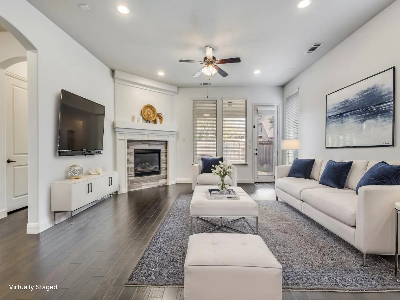 Living area featuring wood-finish flooring, a contemporary fireplace with a stone surround, recessed lighting, and a ceiling fan