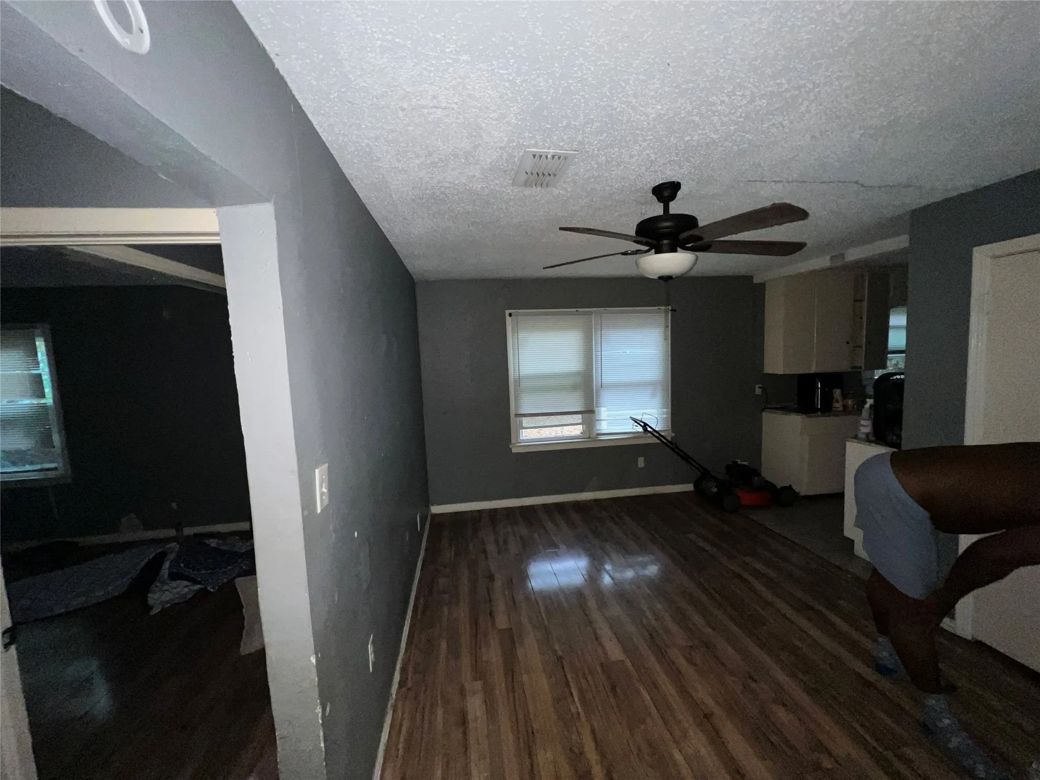 Living room with a textured ceiling, dark wood-style floors, and ceiling fan
