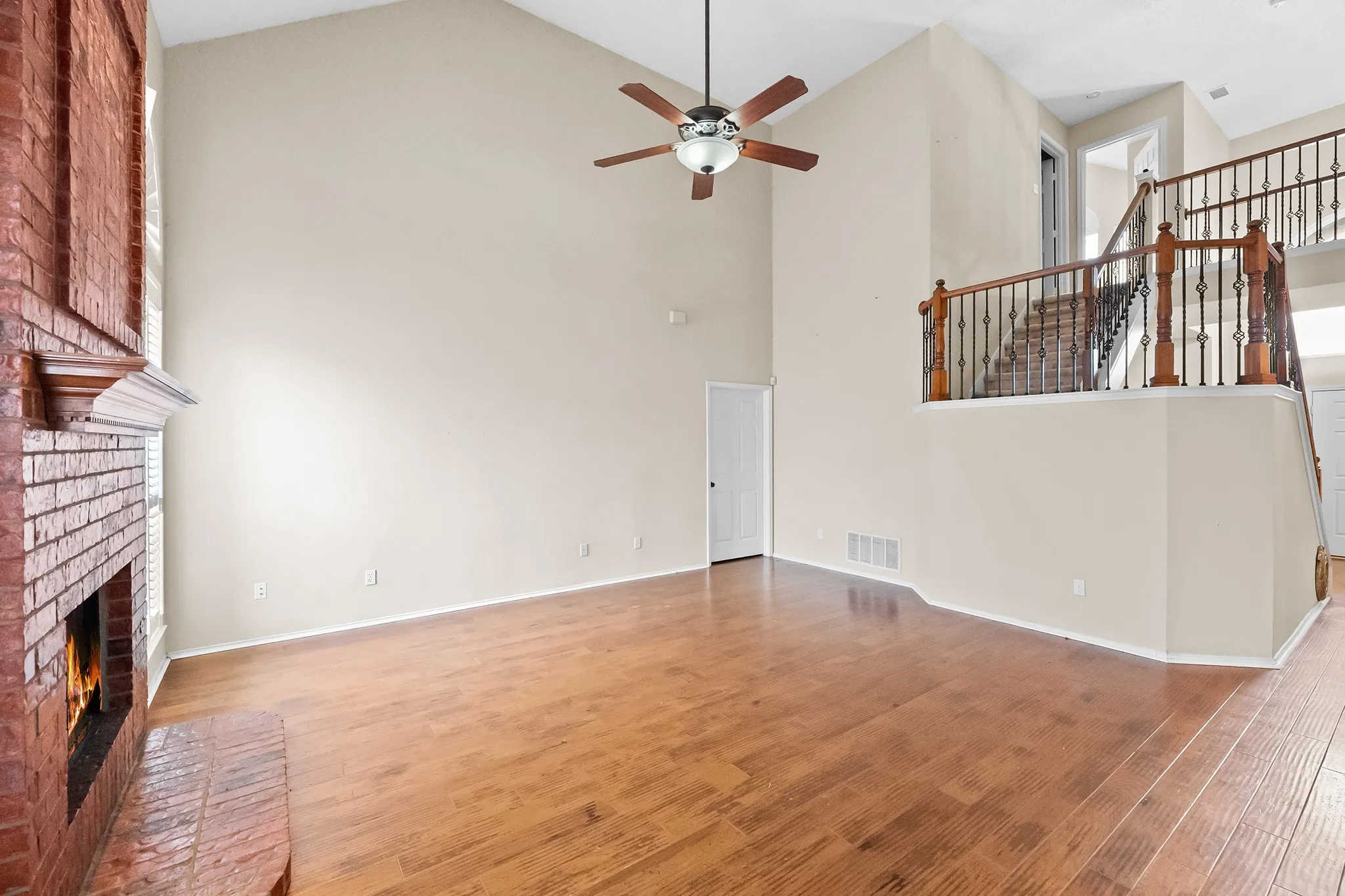 Unfurnished living room featuring high vaulted ceiling, light wood-style floors, ceiling fan, and a fireplace