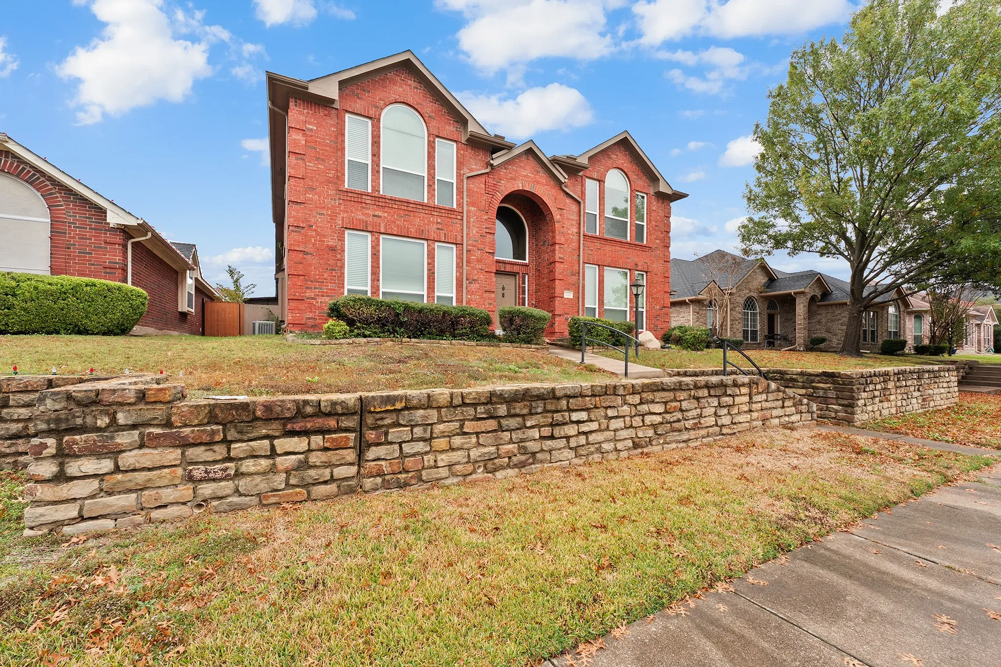 Traditional home with brick siding, a front yard, and a residential view