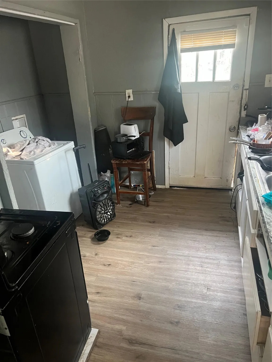 Kitchen with stove, washer / dryer, light wood finished floors, a decorative wall, and a wainscoted wall