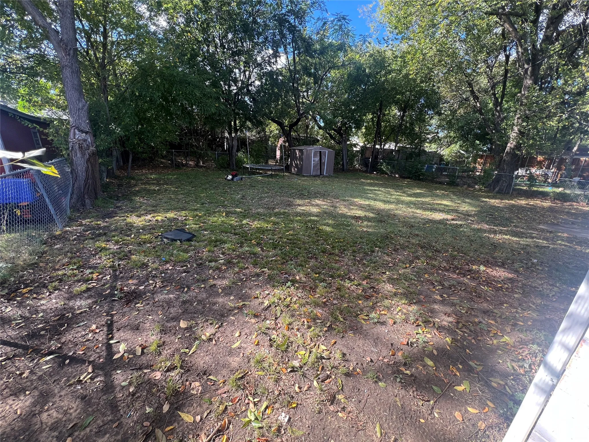 Fenced backyard featuring a shed and view of wooded area