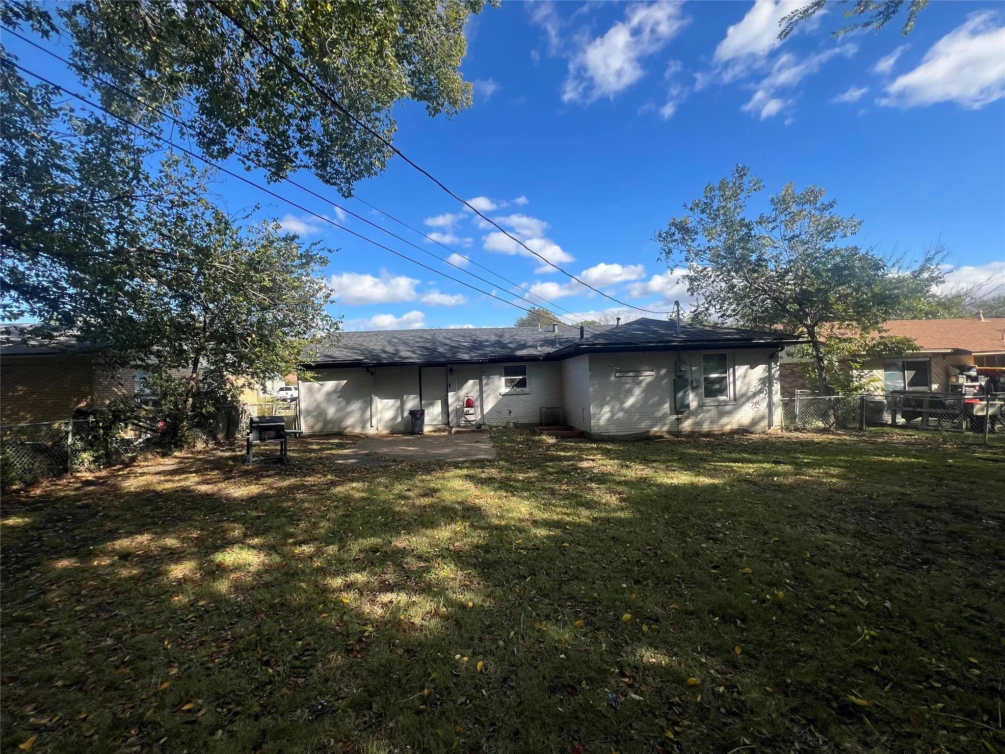Rear view of house with a shingled roof and a patio area