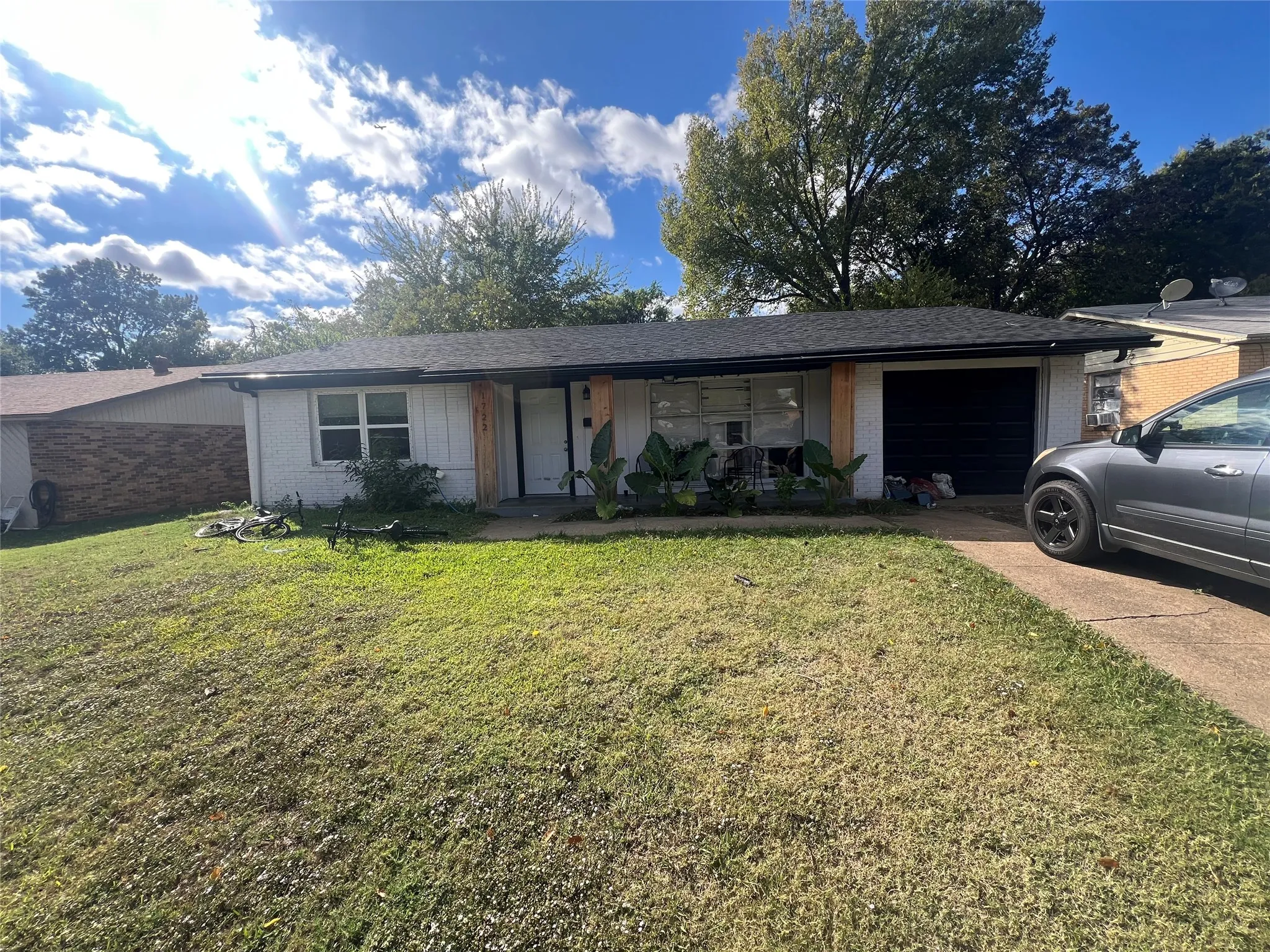 Ranch-style house featuring a front lawn, brick siding, a garage, and driveway