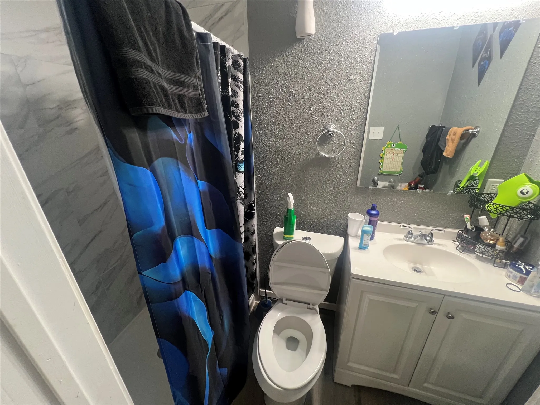 Full bathroom with a stall shower, a textured wall, and vanity