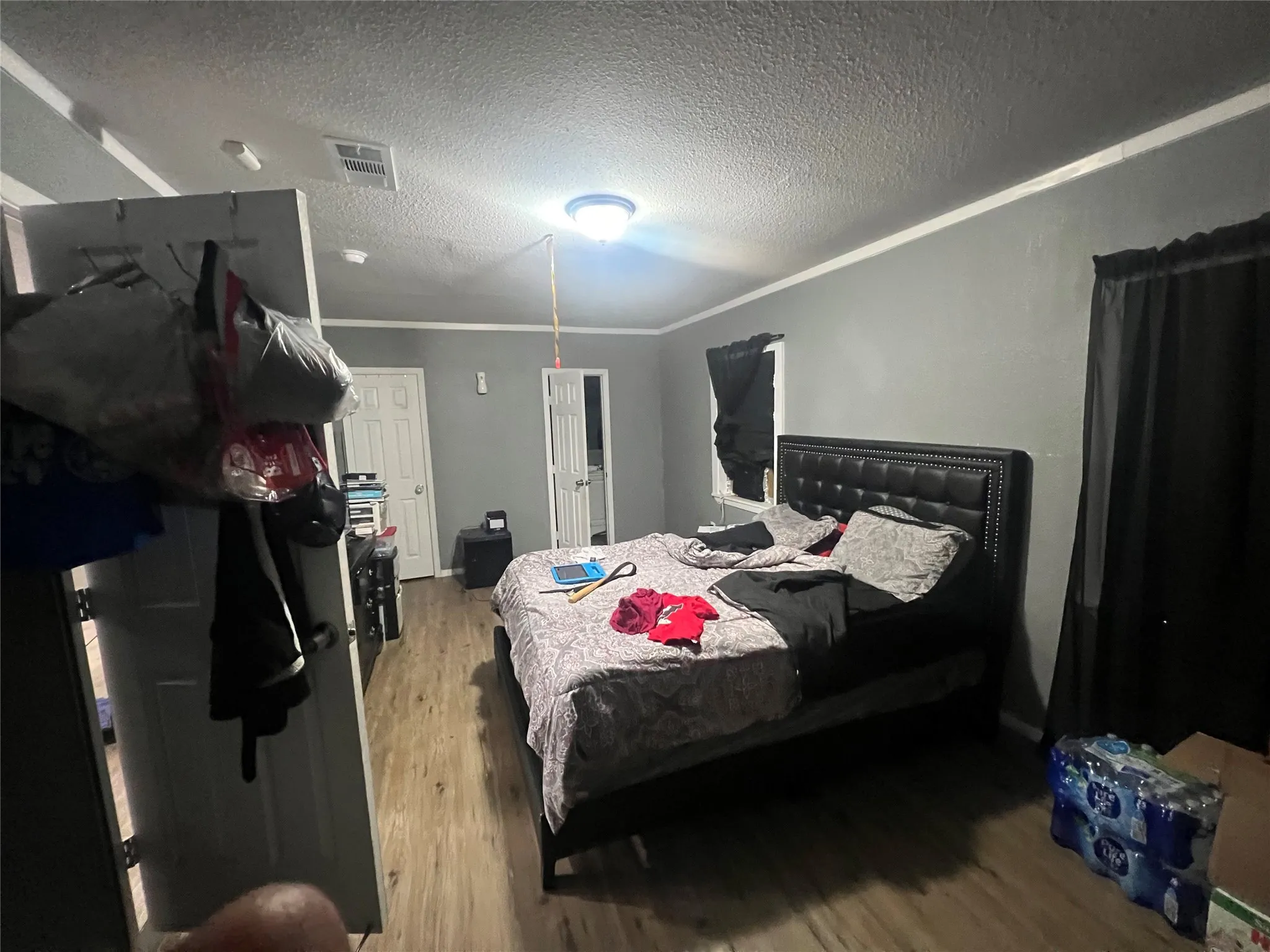 Bedroom featuring a textured ceiling, wood finished floors, and ornamental molding