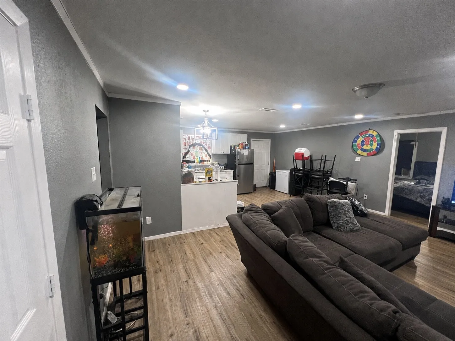 Open-concept living space featuring wood-finish flooring, recessed lighting, crown molding, and a kitchen pass-through with a built-in countertop