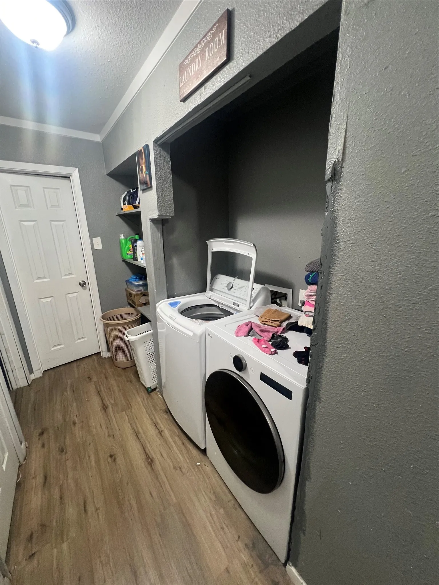 Washroom with a textured wall, wood finished floors, washing machine and dryer, and a textured ceiling