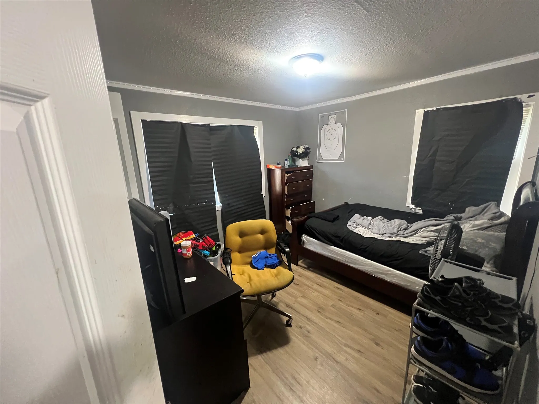 Bedroom with a textured ceiling, light wood-type flooring, crown molding, and a closet