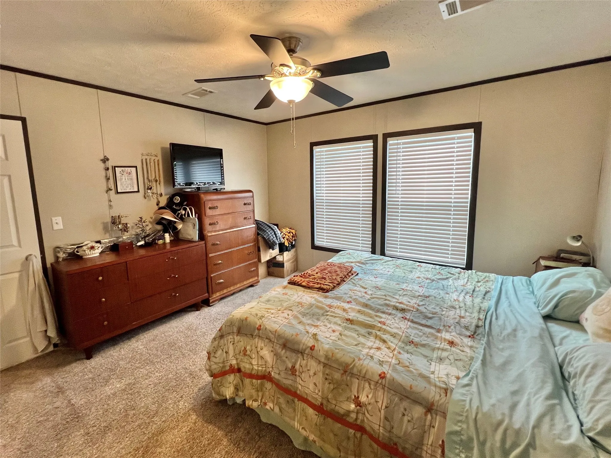 Bedroom with light carpet, crown molding, a textured ceiling, and ceiling fan