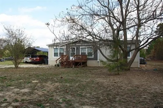 View of front of property featuring a wooden deck and a detached carport
