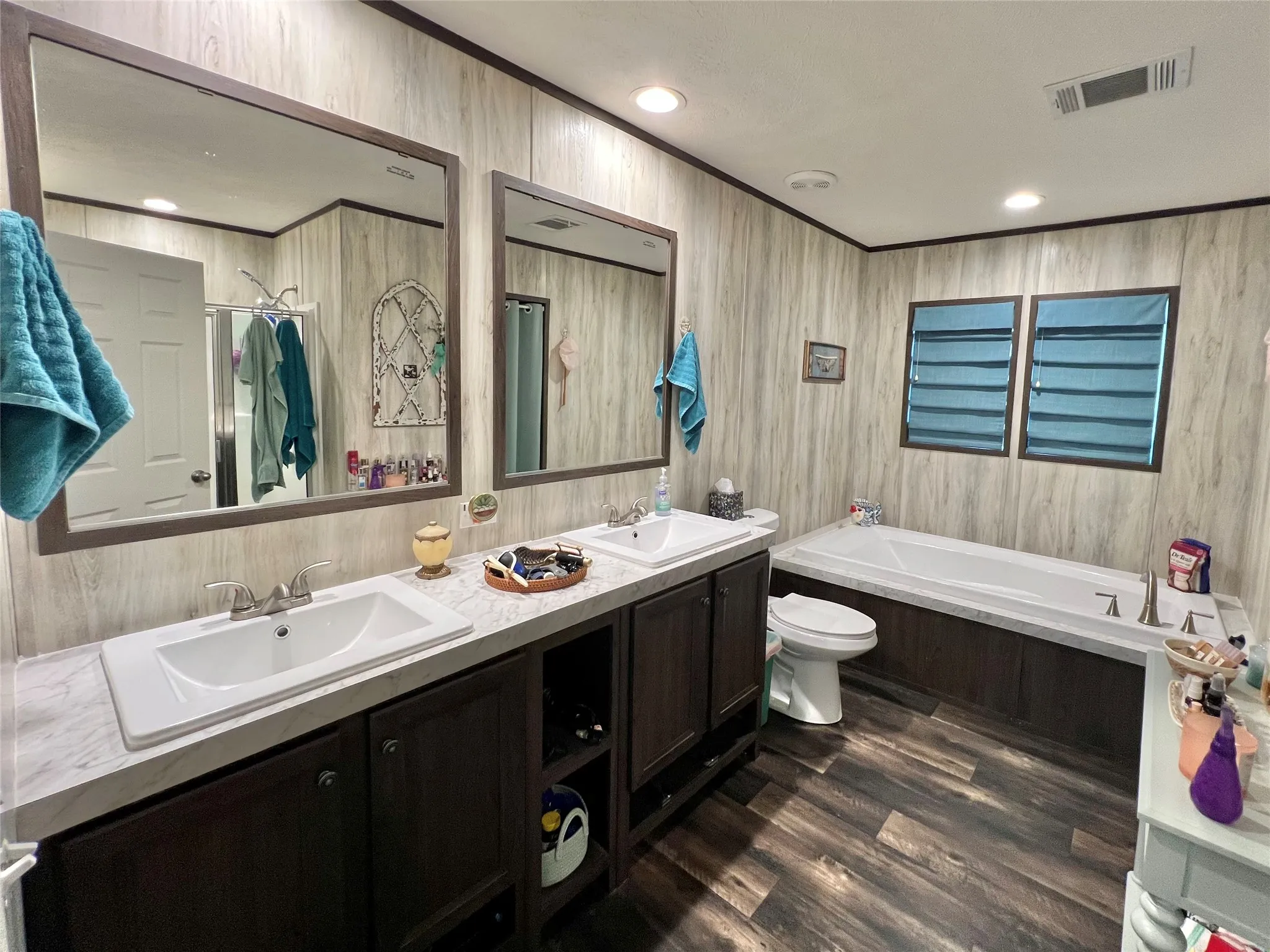 Bathroom with a garden tub, double vanity, dark wood-style flooring, and recessed lighting