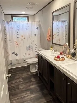 Bathroom featuring dark wood finished floors, double vanity, and ornamental molding