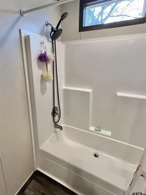 Bathroom featuring bathing tub / shower combination and dark wood finished floors