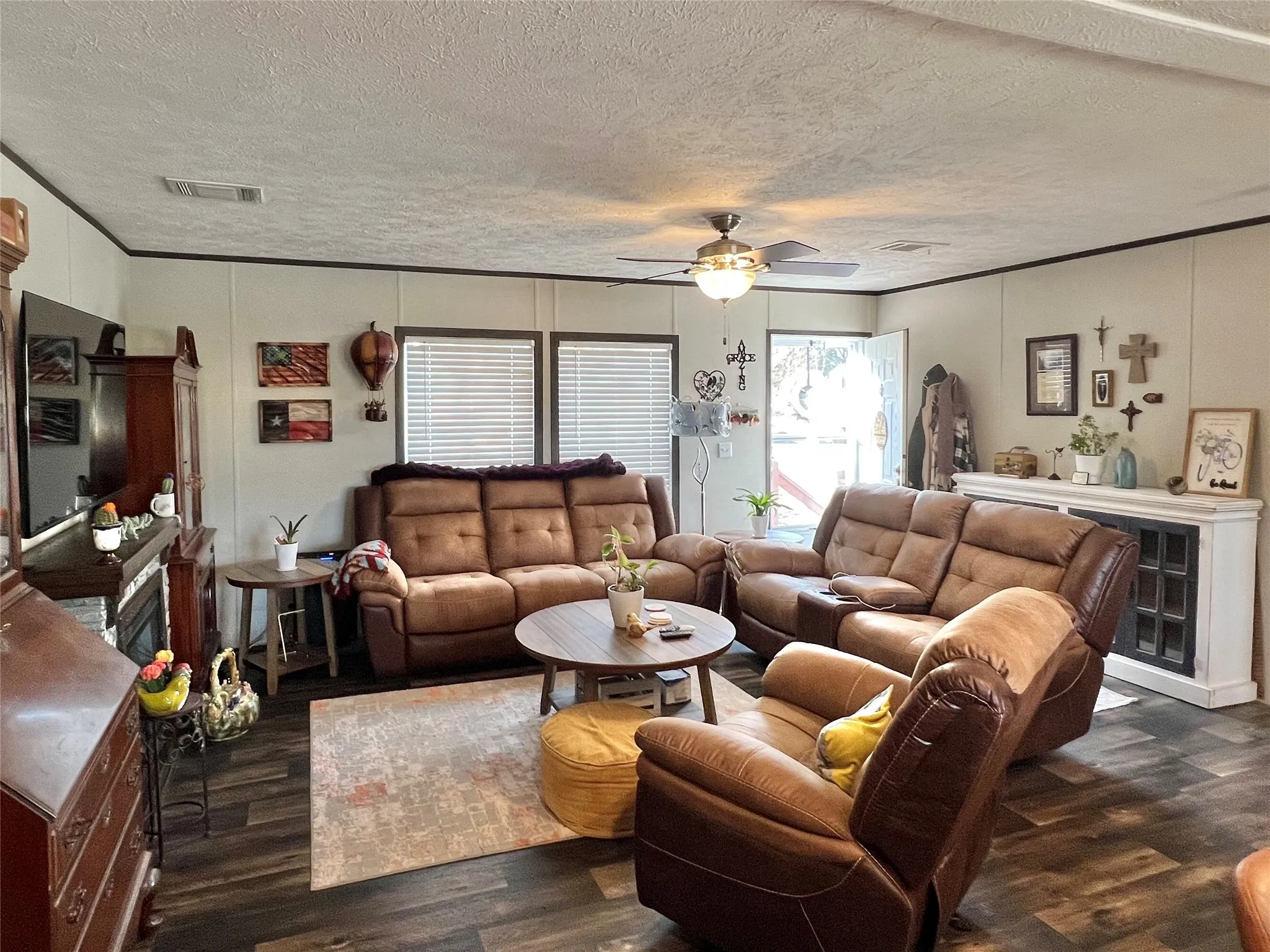 Living area with dark wood-type flooring, a textured ceiling, a decorative wall, and ceiling fan