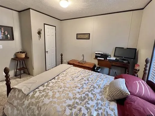 Bedroom featuring a textured ceiling and crown molding