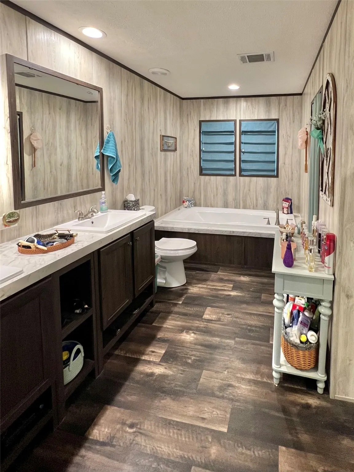 Bathroom featuring a bath, double vanity, dark wood finished floors, recessed lighting, and a textured ceiling