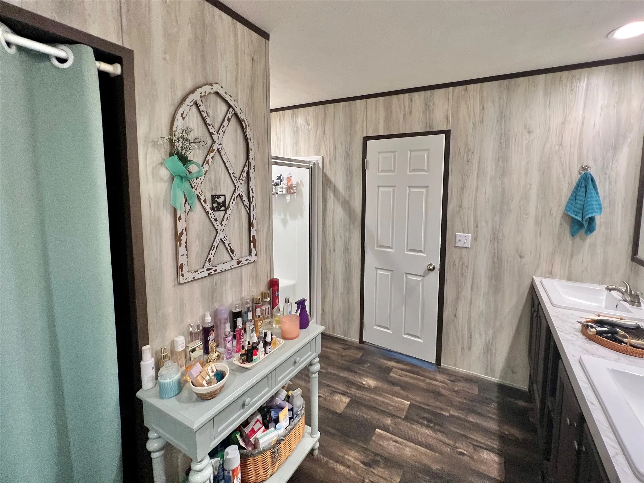 Bathroom with double vanity, dark wood-style floors, and wood walls