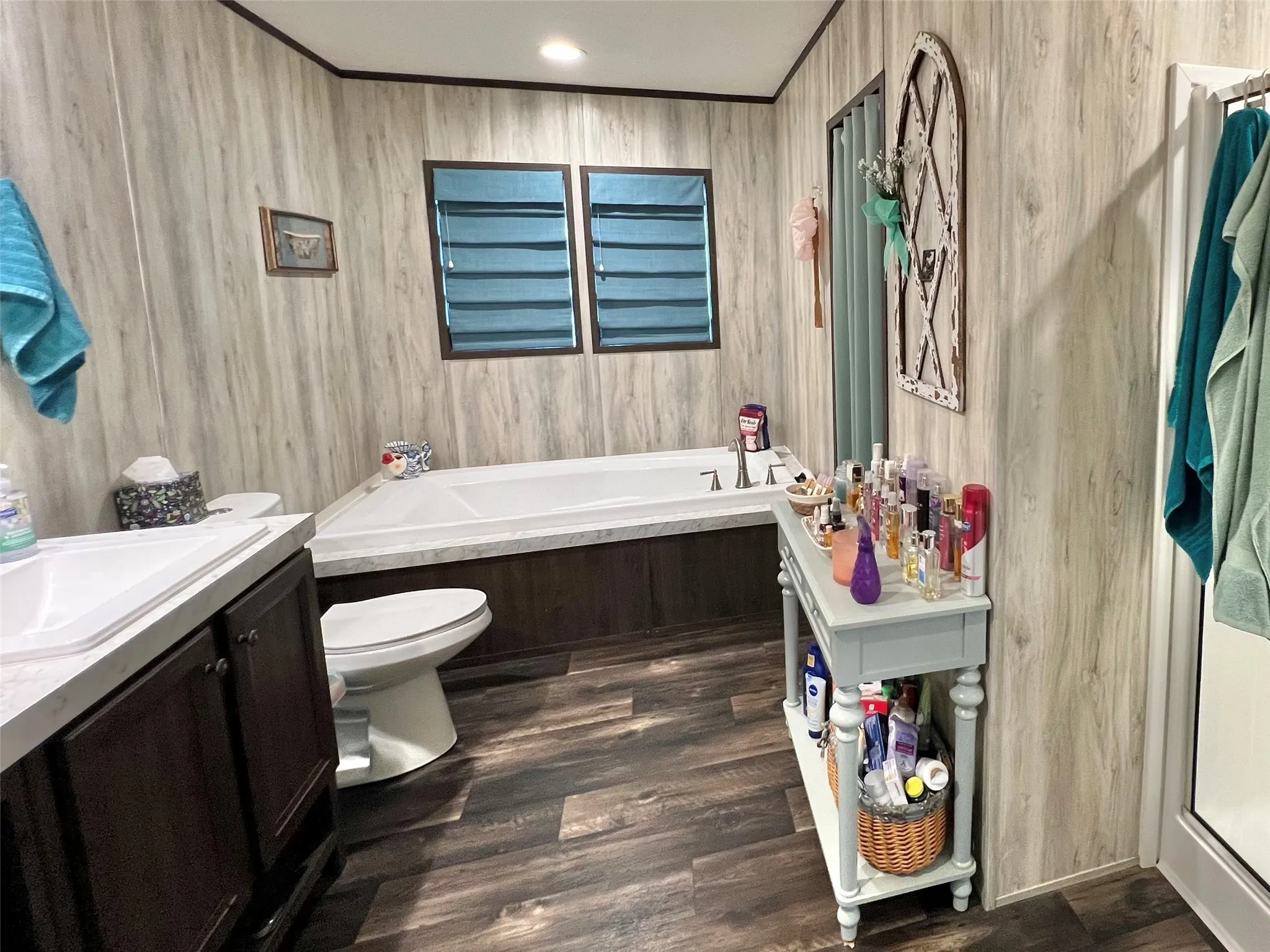 Full bathroom with a garden tub, vanity, dark wood-style flooring, recessed lighting, and ornamental molding