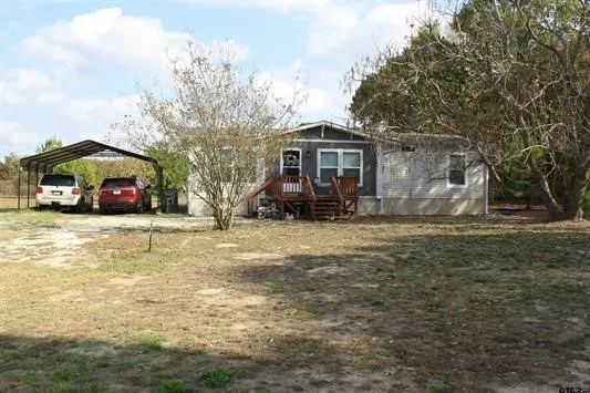 View of front facade featuring a detached carport, driveway, and a wooden deck