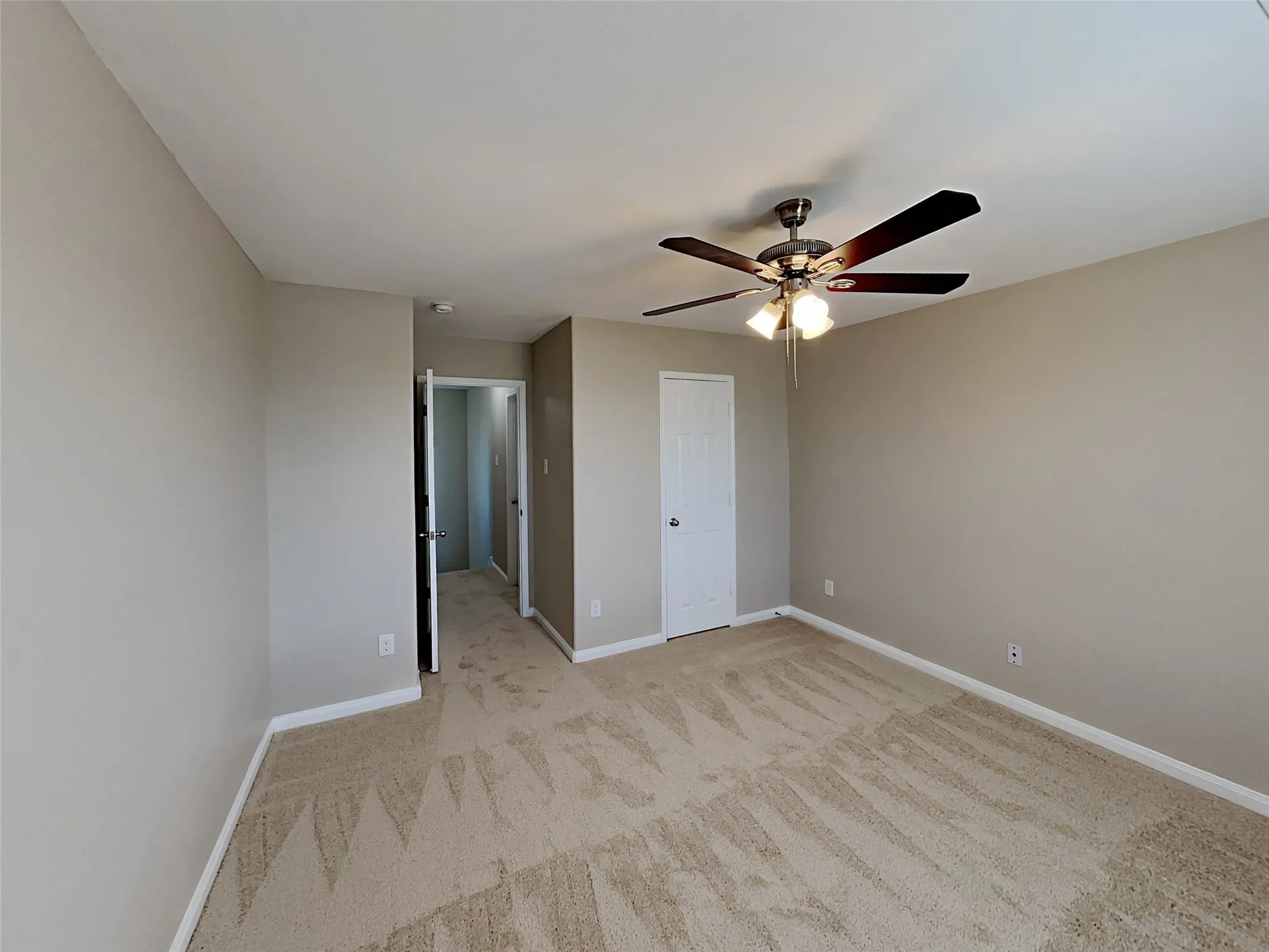 Unfurnished bedroom featuring light carpet and ceiling fan