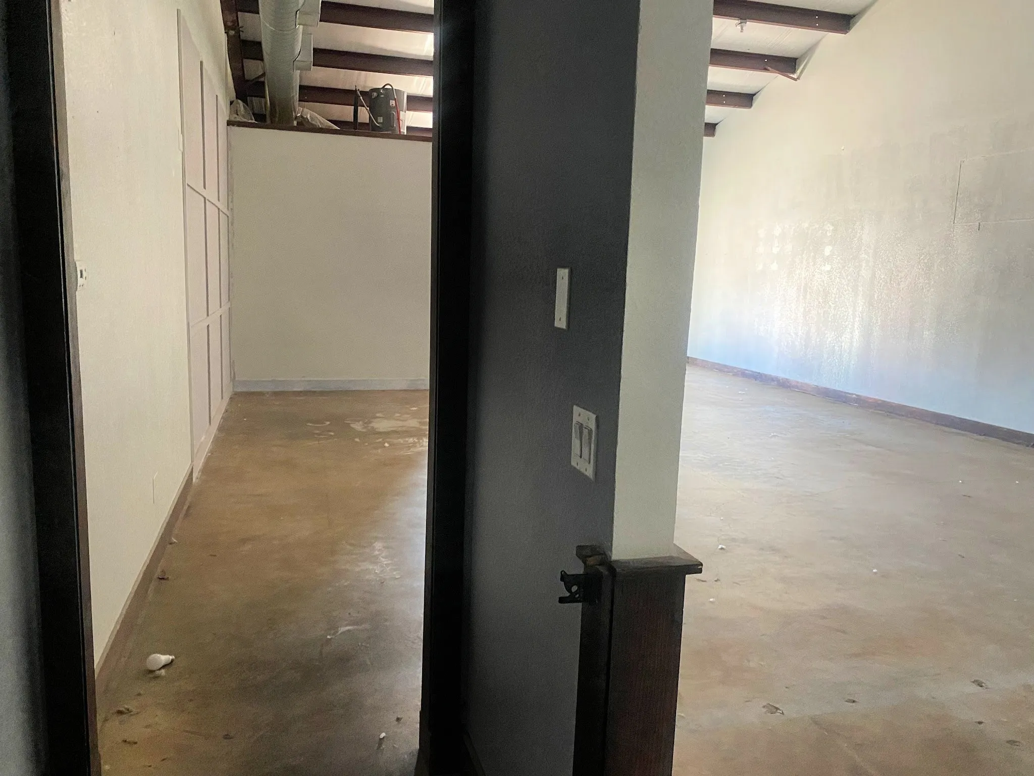 Hallway with unfinished concrete flooring and baseboards