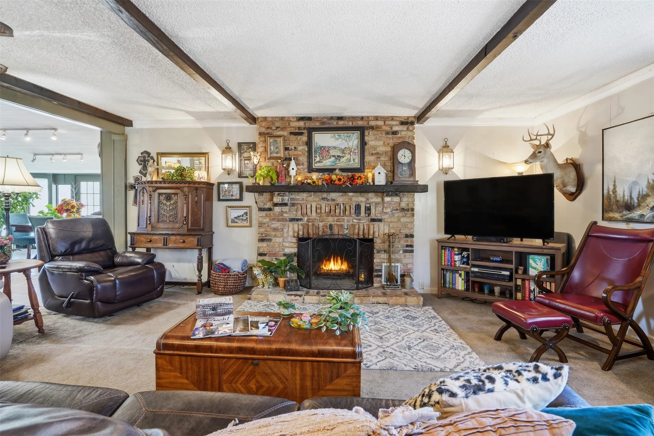 Carpeted living room featuring beamed ceiling, a textured ceiling, and a fireplace