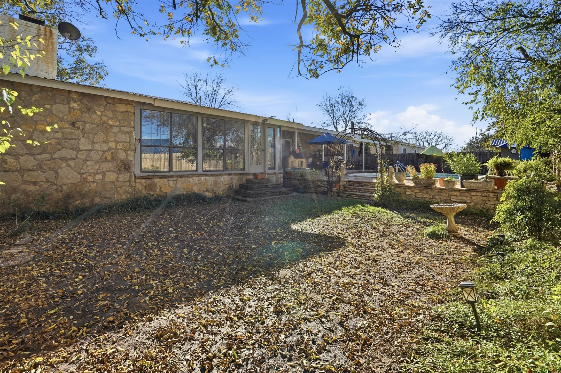Rear view of property with stone siding, a patio, and a chimney