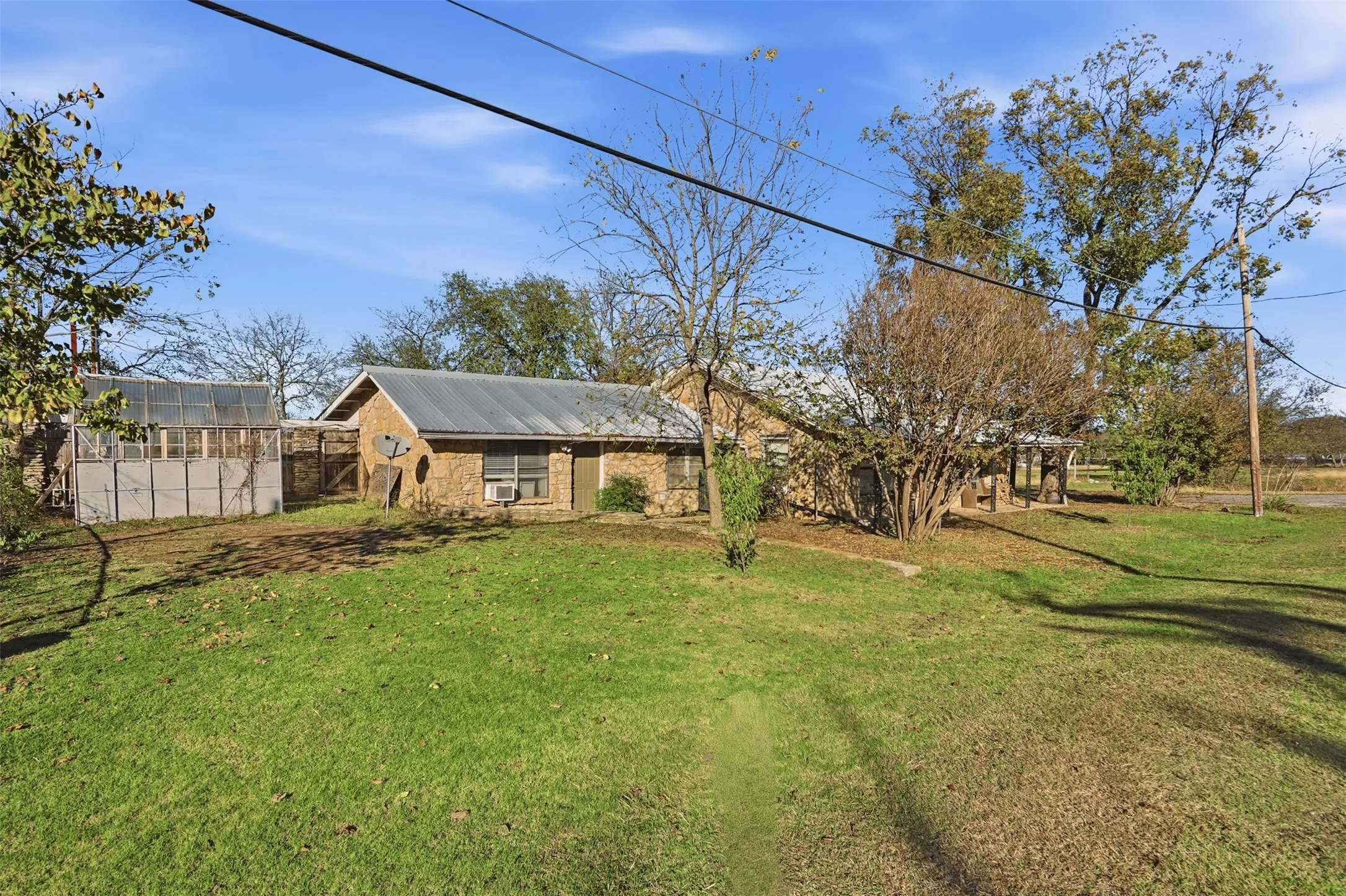 View of front of house with an outbuilding, a greenhouse, and a front yard