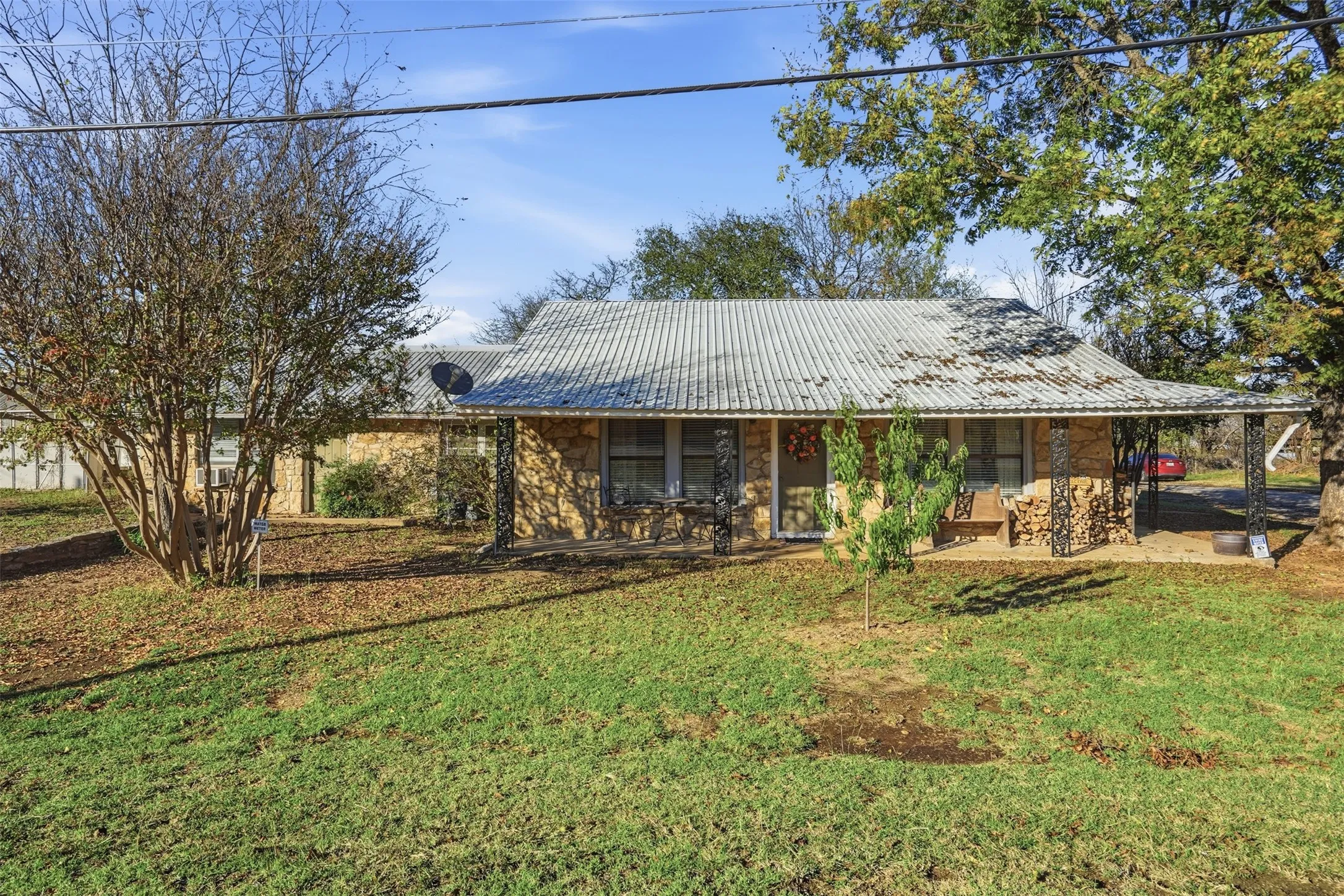 View of front of home with stone siding, a metal roof, and a front lawn