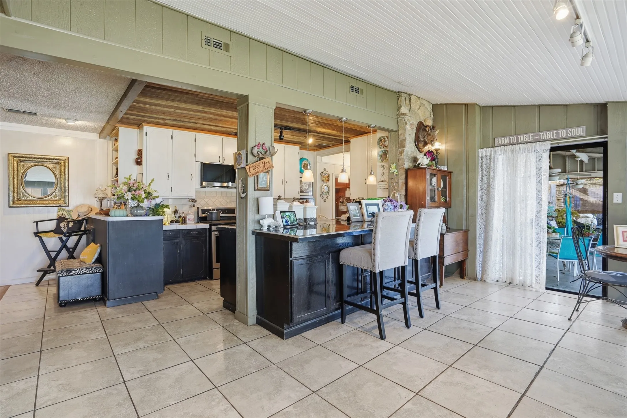 Kitchen with a breakfast bar area, white cabinets, light tile patterned floors, and appliances with stainless steel finishes