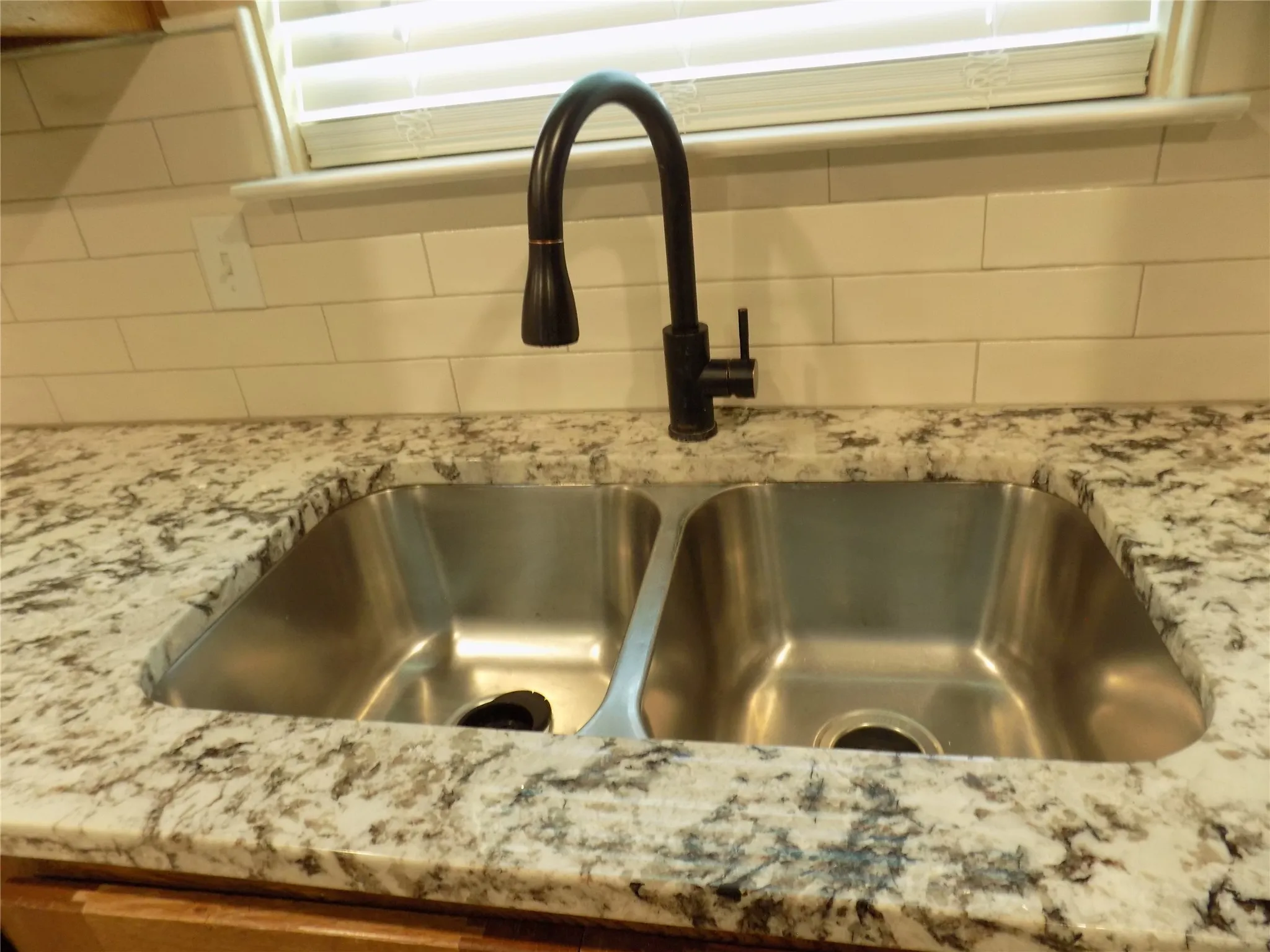 Double, under cabinet stainless steel sink with window.