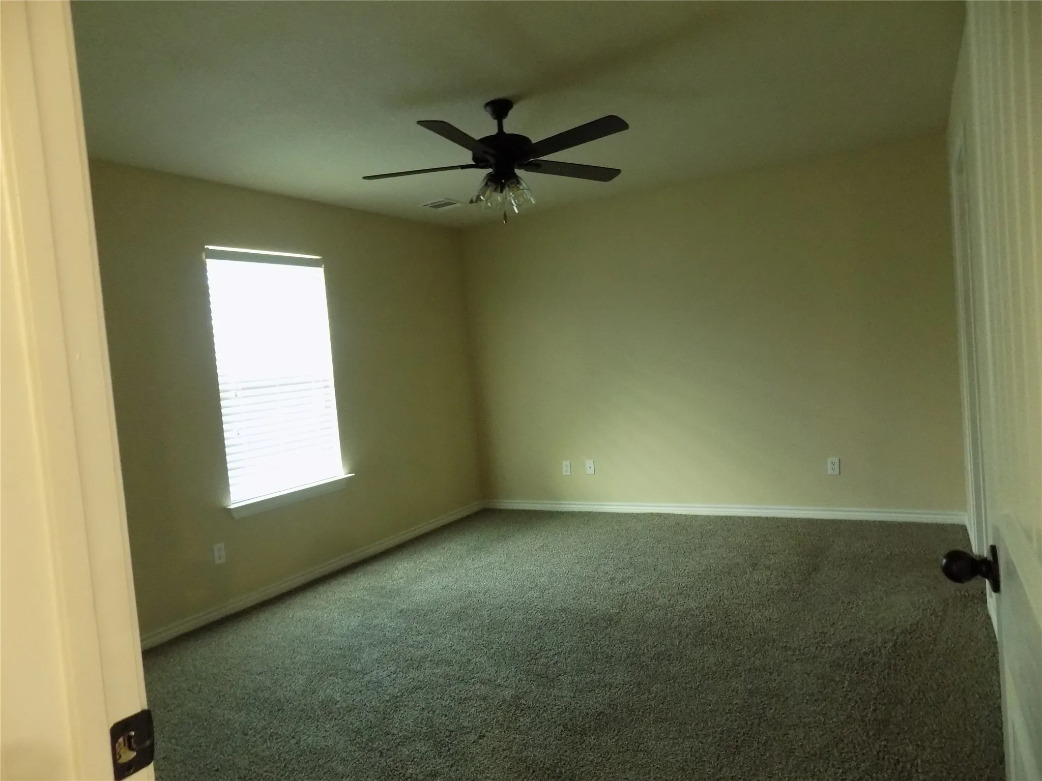 Lovely primary bedroom with large window, ceiling fan, and ensuite bathroom.