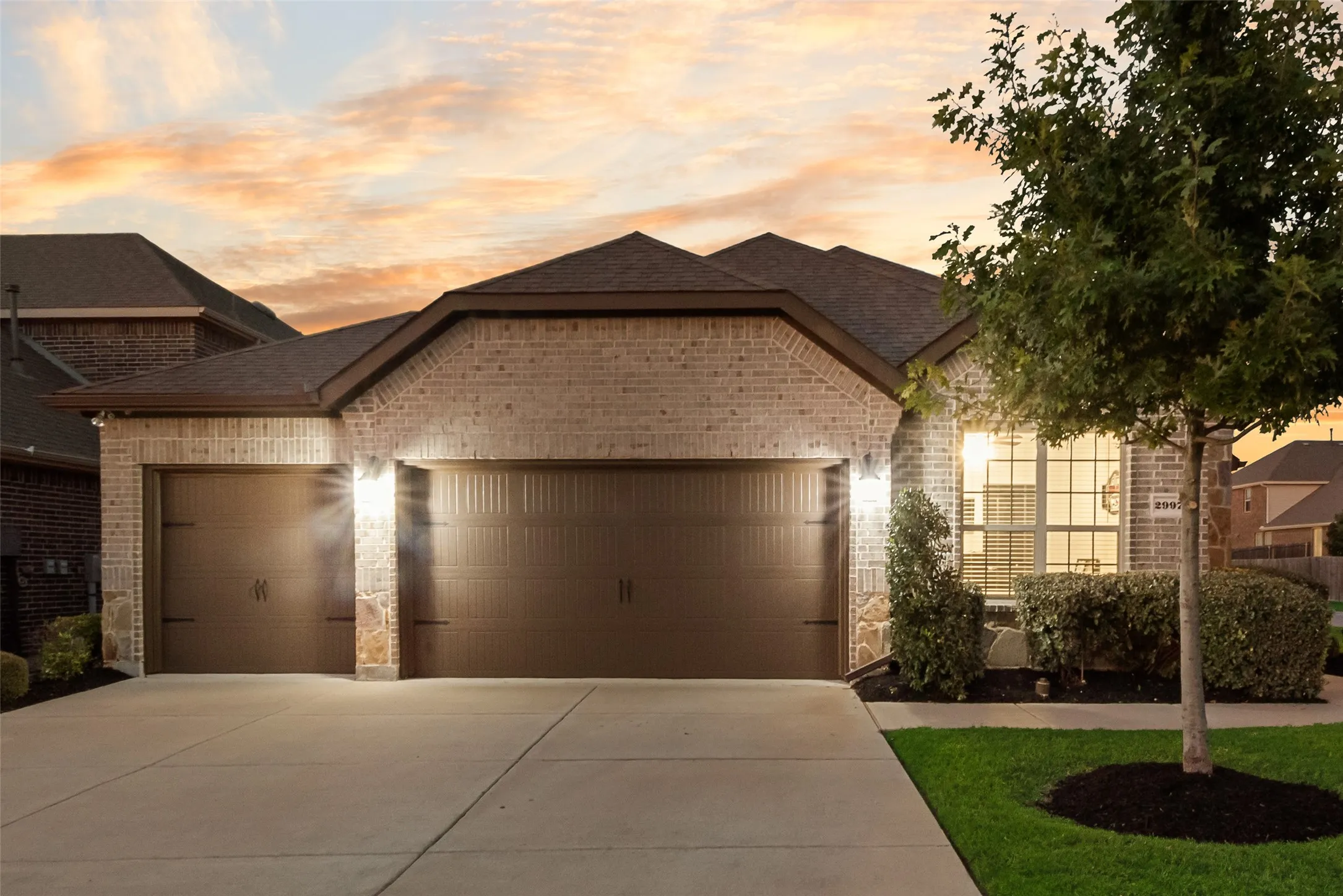 View of front of property with brick siding, a garage, roof with shingles, and driveway