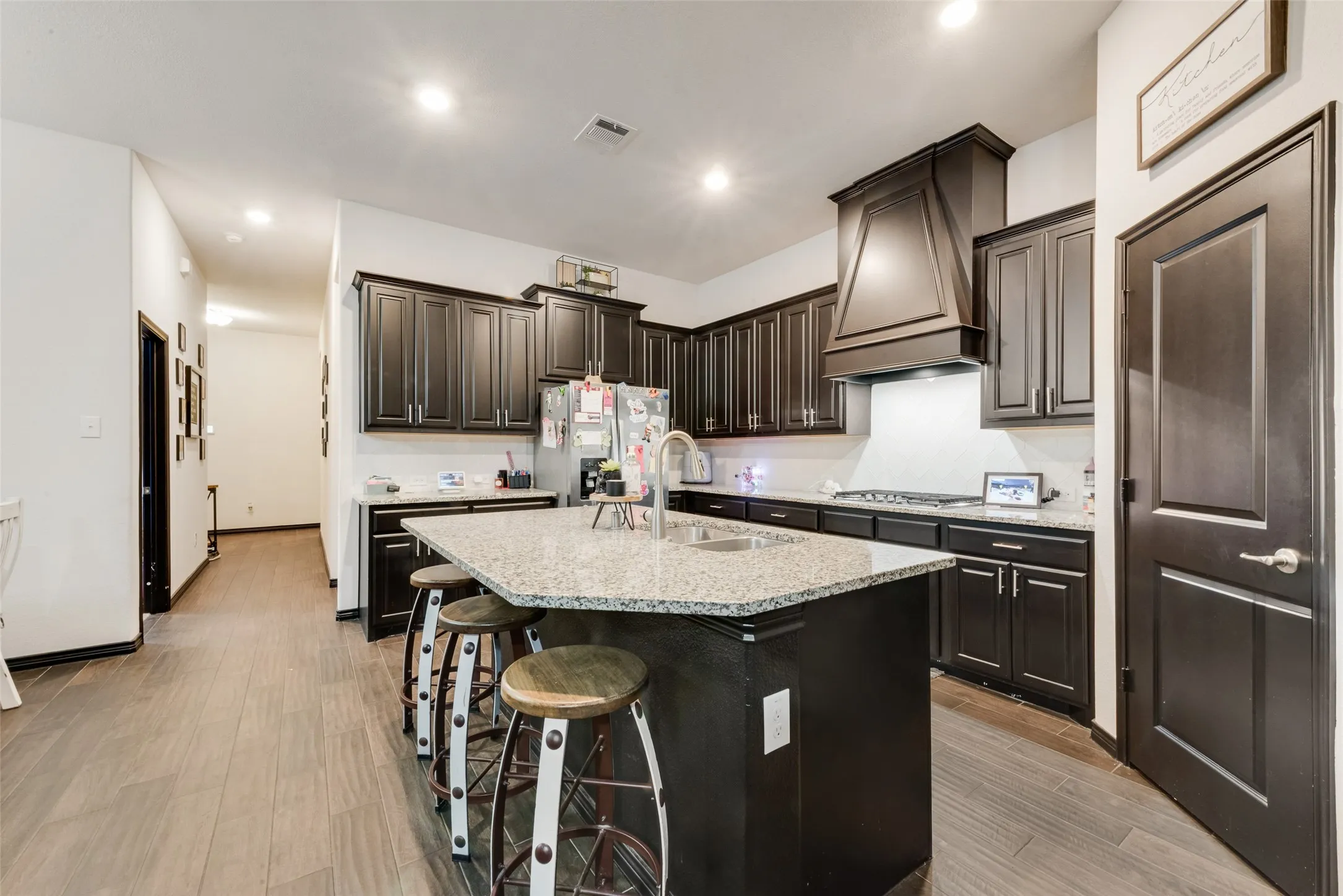 Kitchen featuring a breakfast bar area, appliances with stainless steel finishes, an island with sink, recessed lighting, and light stone counters