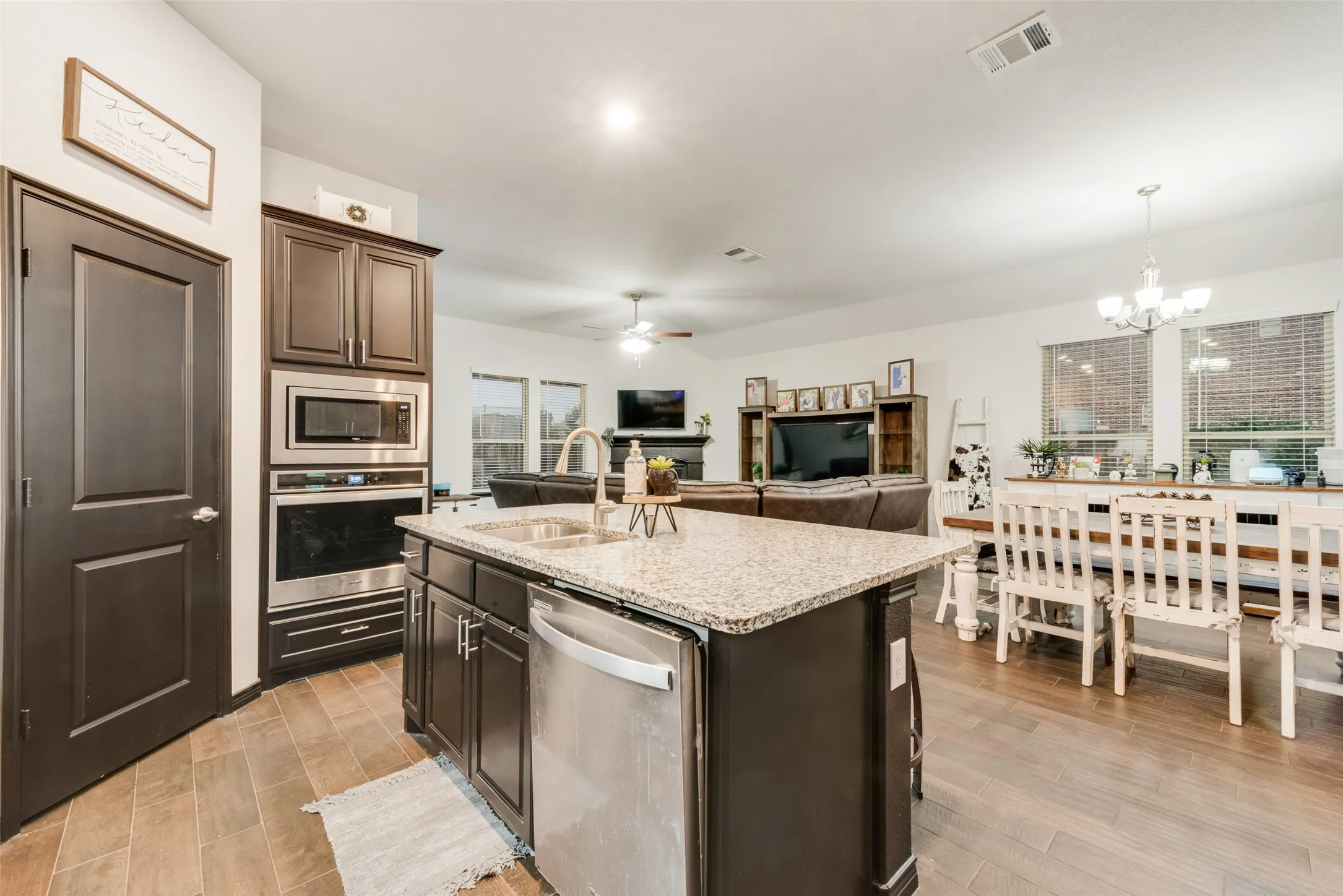Kitchen with stainless steel appliances, ceiling fan, light stone counters, and light wood finished floors