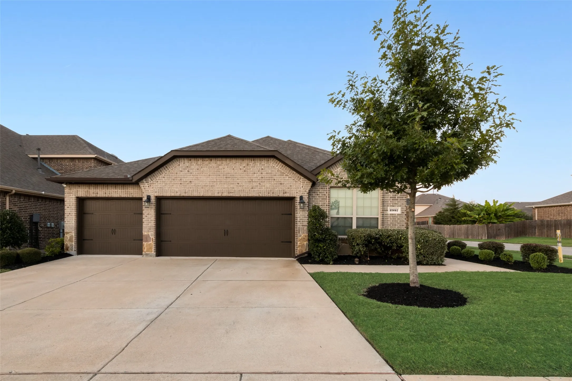 View of front of house with brick siding, an attached garage, concrete driveway, and roof with shingles