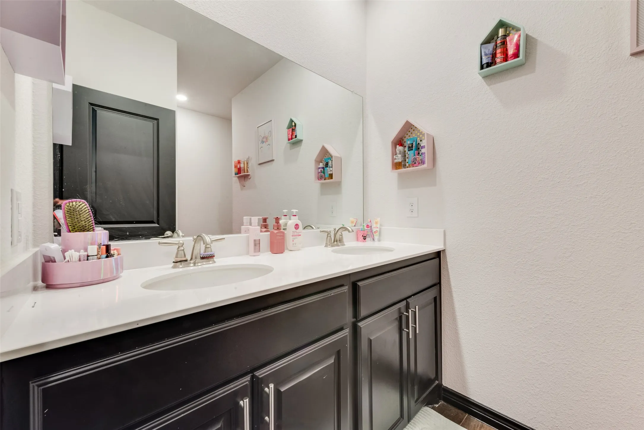 Full bath with double vanity, a textured wall, and recessed lighting