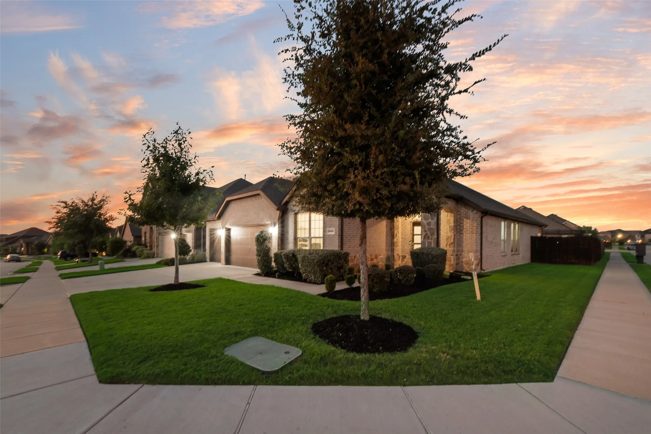 View of property hidden behind natural elements with concrete driveway, brick siding, a front lawn, and an attached garage