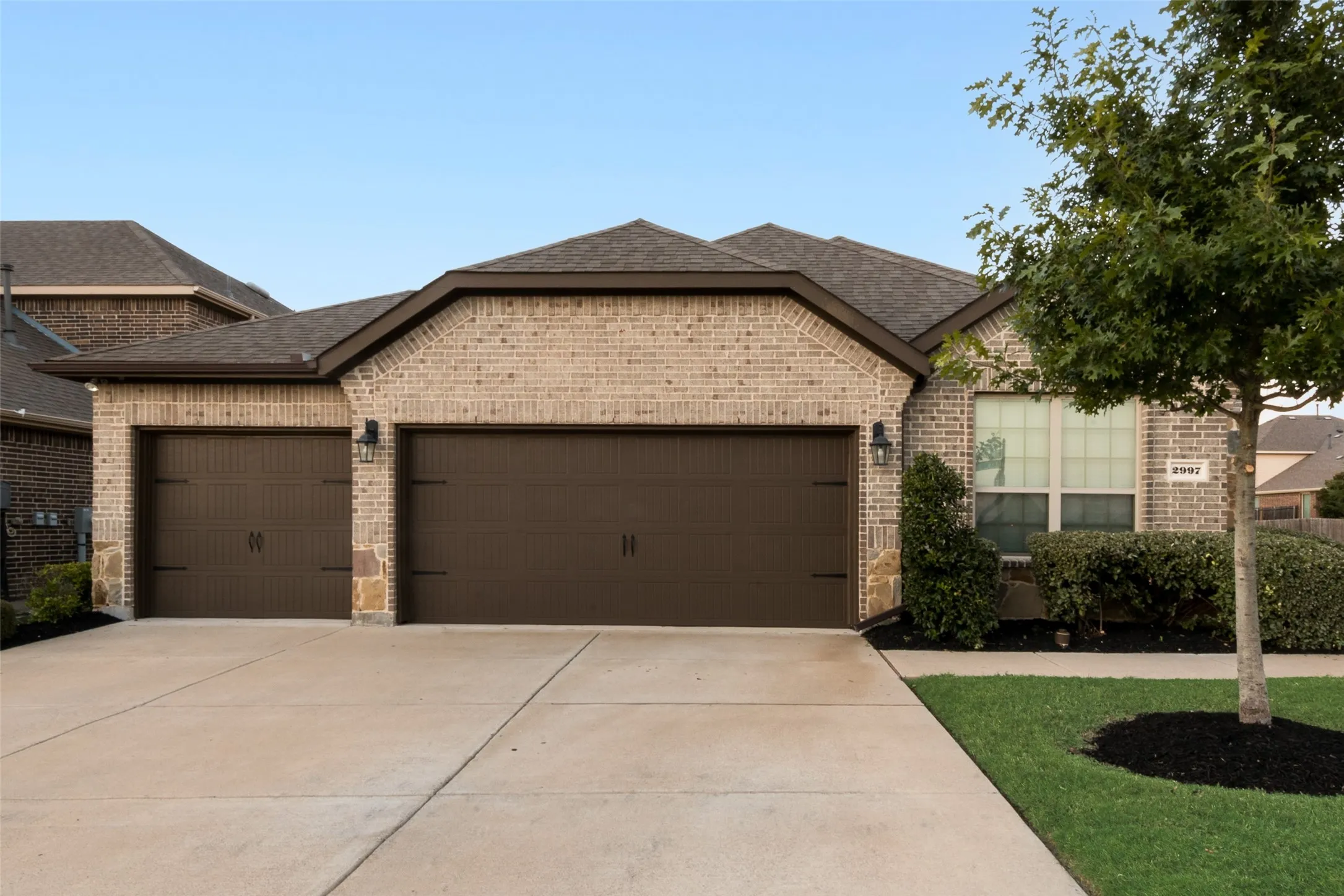 View of front of house featuring a garage, brick siding, roof with shingles, and driveway