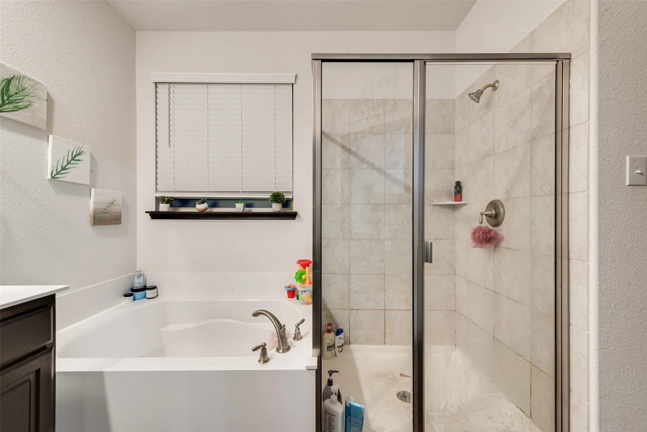 Bathroom with vanity, a bath, a stall shower, and a textured wall