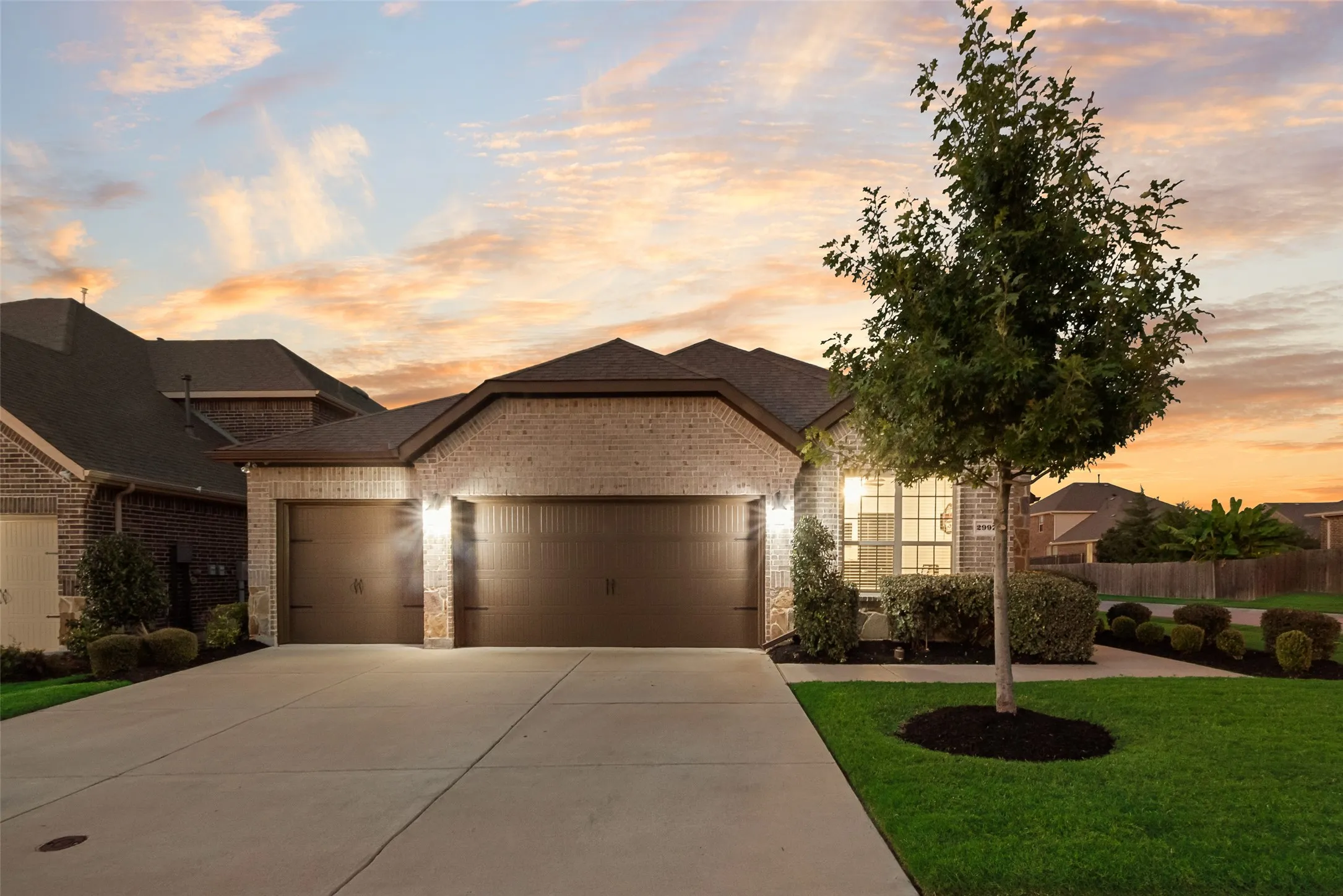 French provincial home with a garage, brick siding, driveway, and roof with shingles